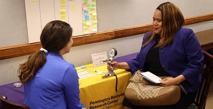 Study participant hold a grip strength tester with test administrator