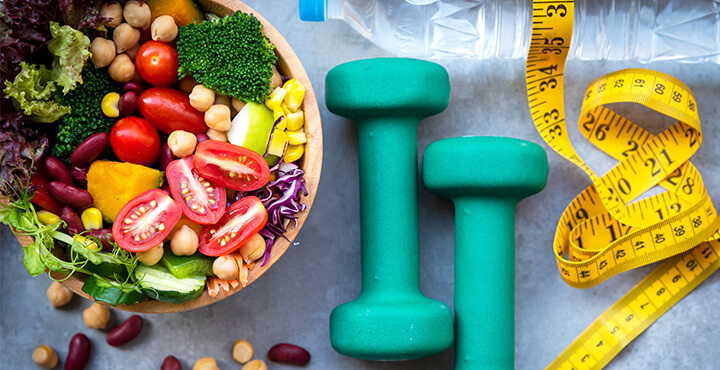 Regulating Weight - Image depicts exercise equipment and a healthy foods.